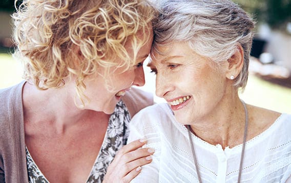 mother with a medical alert pendant and daughter smile at one another