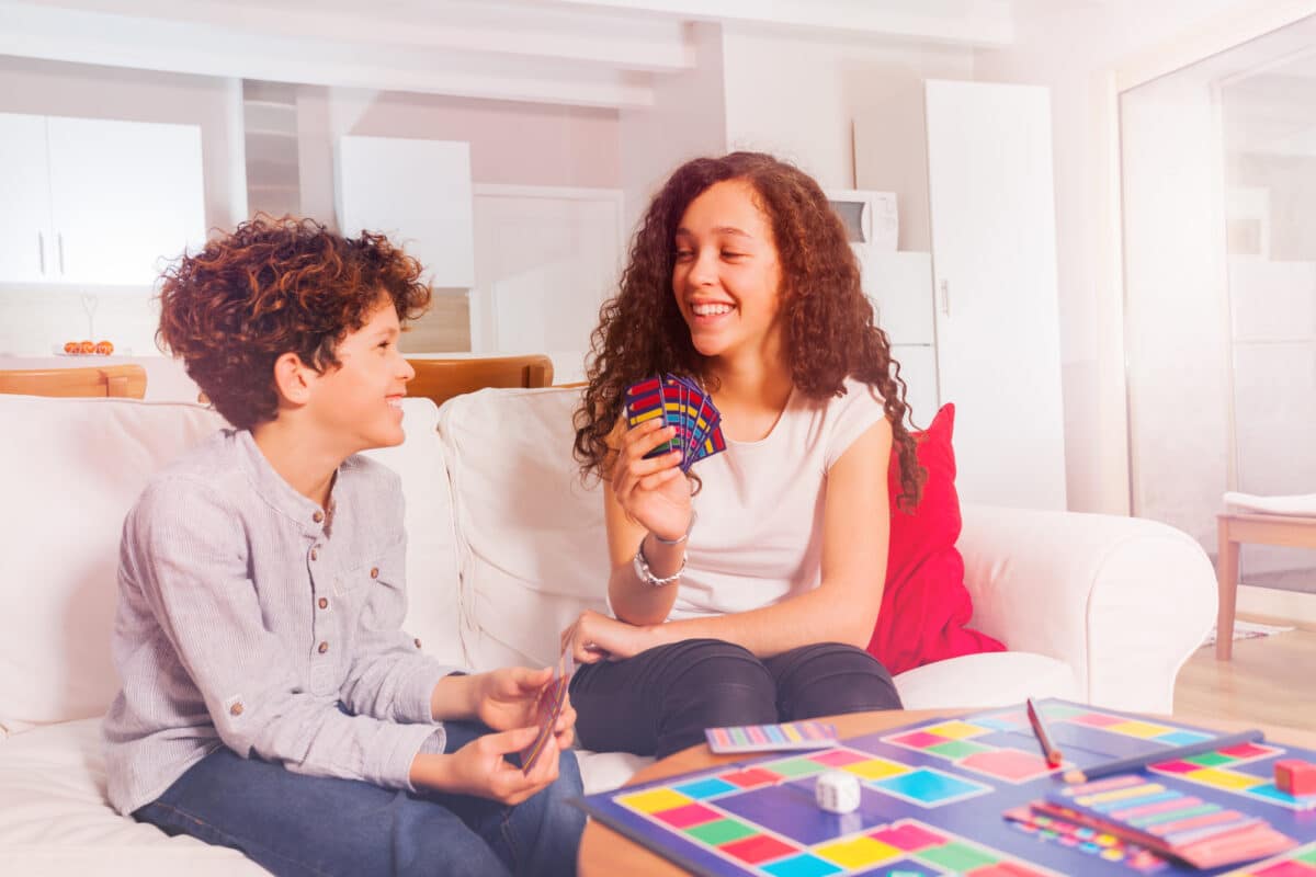 young male and female siblings play a card game at home for some safe summer fun